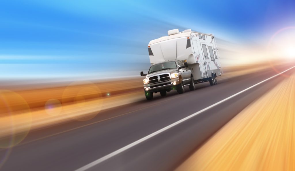 Truck with RV trailer driving through a desert